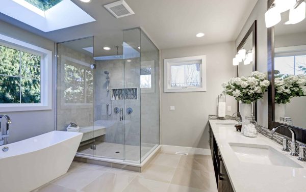 Spacious bathroom in gray tones with heated floors, freestanding tub, walk-in shower, double sink vanity and skylights. Northwest, USA